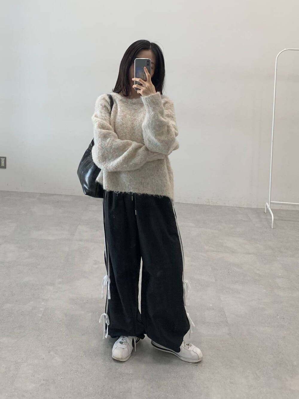 ブラック系のその他パンツ、ホワイト系のニット/セーター、ブラック系のハンドバッグを着用したレディースの秋コーディネートの2枚目の写真