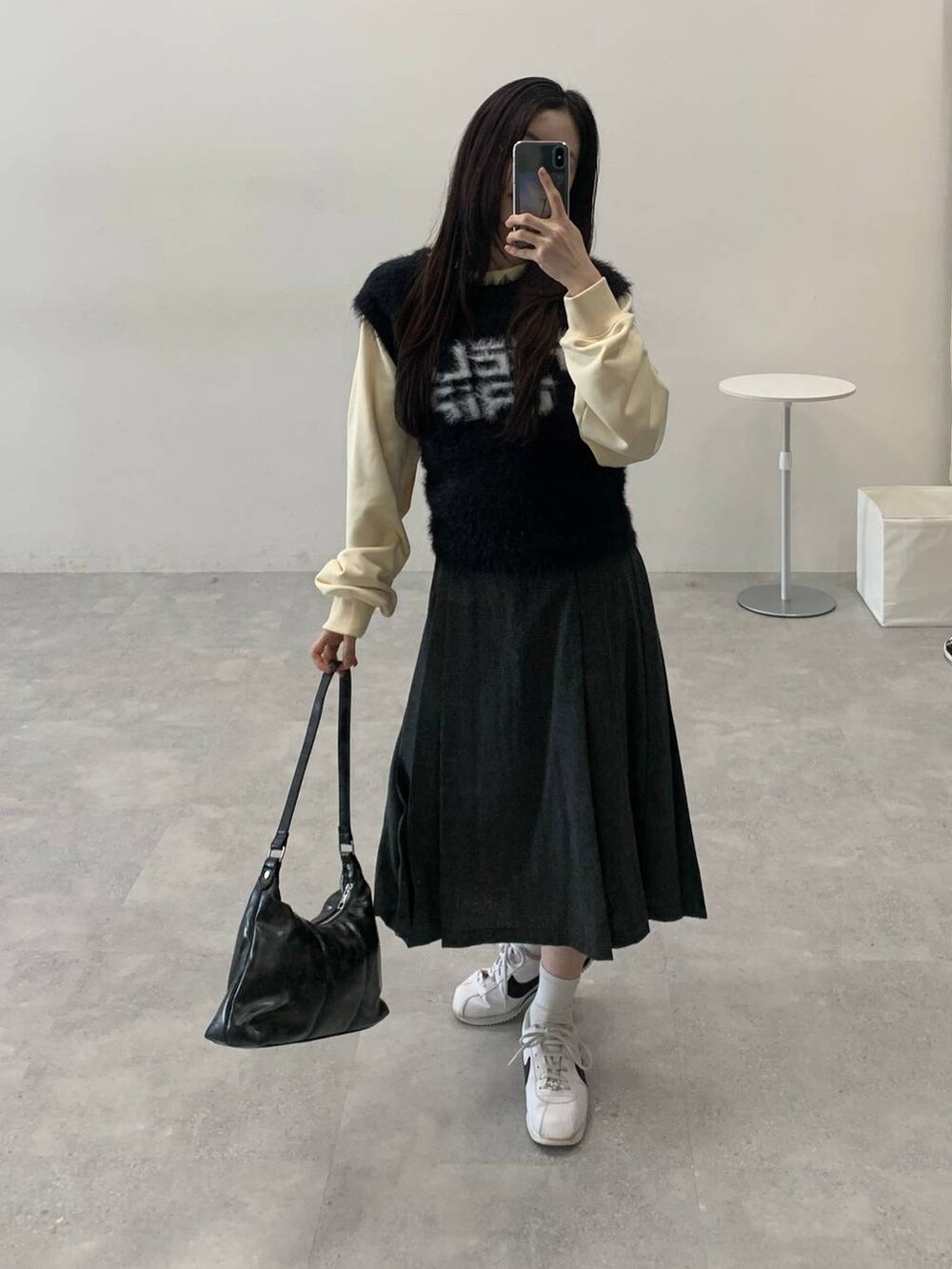 ベージュ系のスウェット、グレー系のスカート、ブラック系のハンドバッグを着用したレディースの冬コーディネートの2枚目の写真