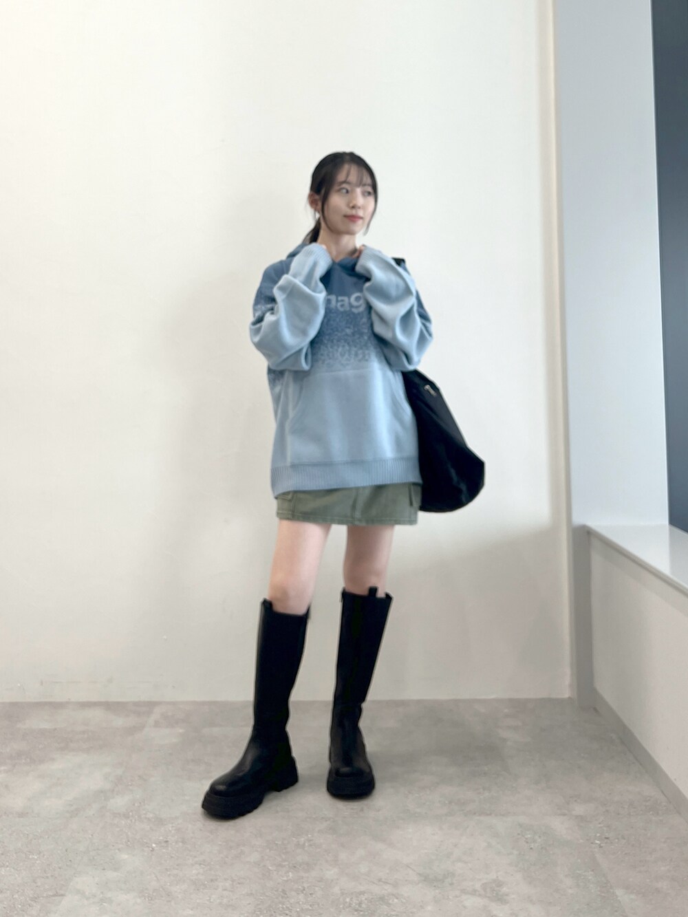ブラック系のブーツ、ブルー系のニット/セーター、ブラック系のショルダーバッグを着用したレディースの秋コーディネートの2枚目の写真