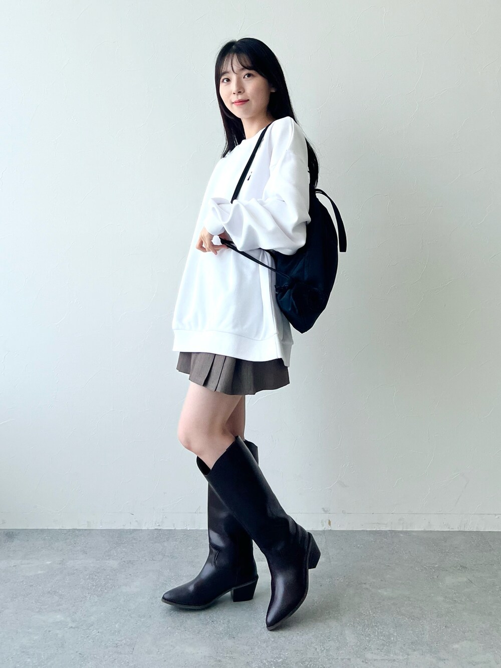 ブラック系のブーツ、ブラウン系のスカート、ホワイト系のスウェットを着用したレディースの冬コーディネートの3枚目の写真