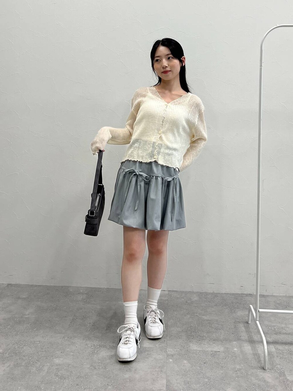 グレー系のスカート、ブラック系のトートバッグ、ベージュ系のカーディガン/ボレロを着用したレディースの夏コーディネートの3枚目の写真