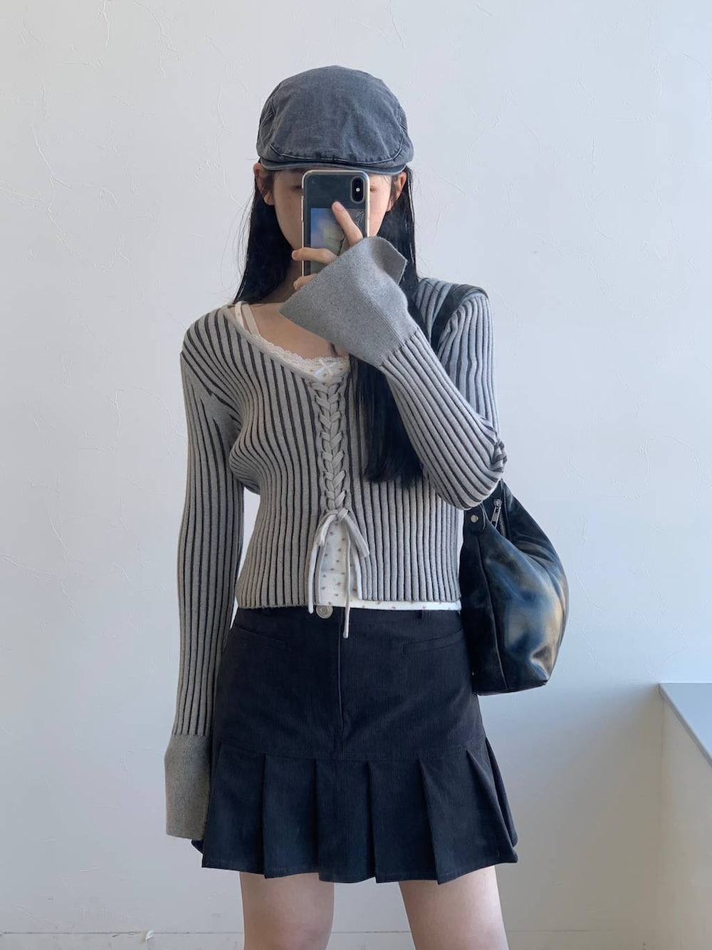 グレー系のカーディガン/ボレロ、グレー系のスカート、ブラック系のハンドバッグを着用したレディースの冬コーディネートの5枚目の写真