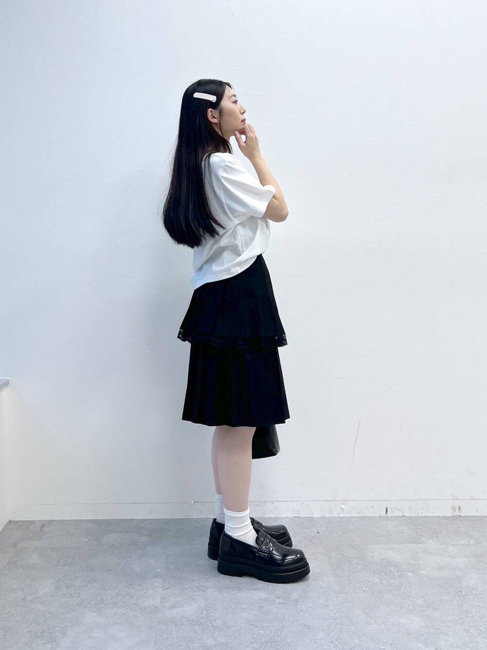 ブラック系のスカート、ホワイト系のTシャツ/カットソー、ブラック系のハンドバッグを着用したレディースの夏コーディネートの6枚目の写真