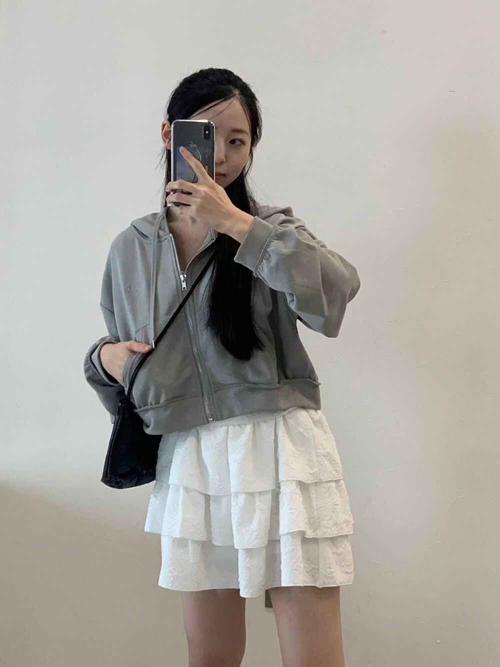 グレー系のパーカー、ホワイト系のスカートを着用したレディースの秋コーディネートの6枚目の写真