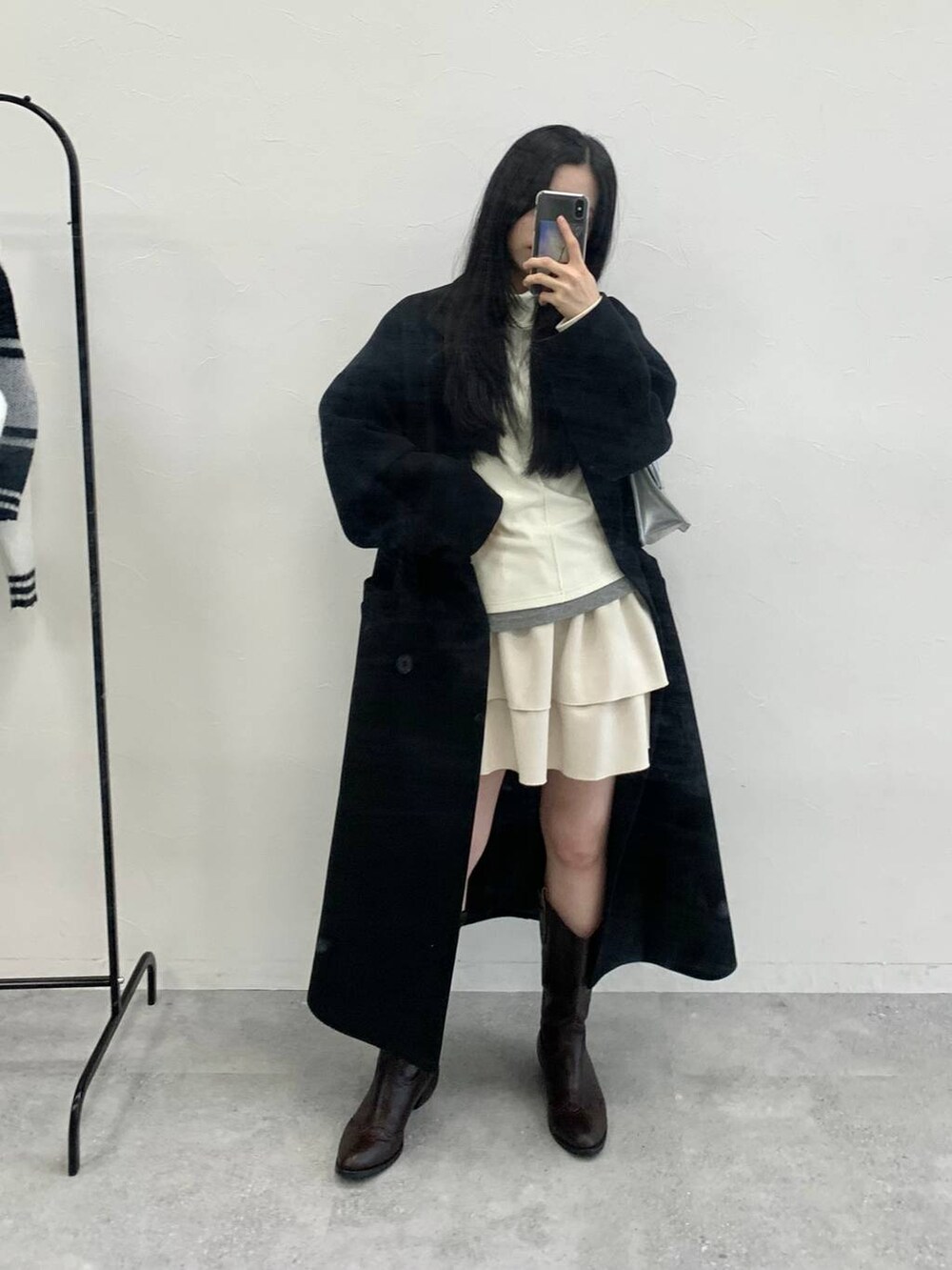 シルバー系のショルダーバッグ、ベージュ系のTシャツ/カットソー、ホワイト系のスカートを着用したレディースの冬コーディネートの6枚目の写真