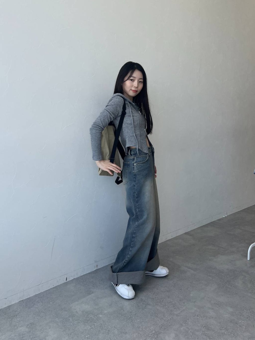 ブルー系のデニムパンツ、グレー系のTシャツ/カットソー、ベージュ系のバックパック/リュックを着用したレディースの春コーディネートの3枚目の写真