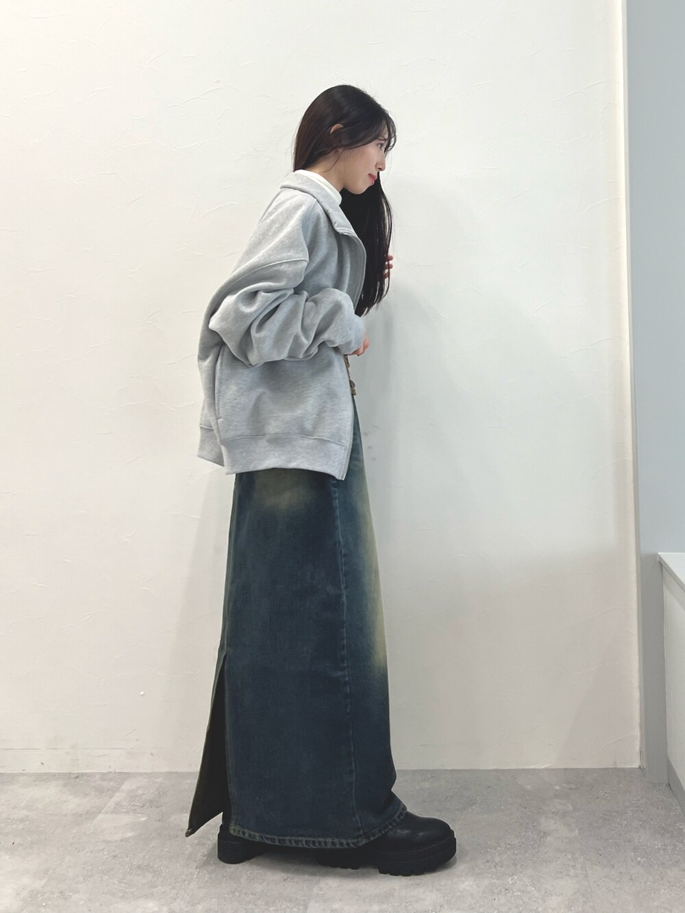 ブラック系のブーツ、ブルー系のデニムスカート、ベージュ系のTシャツ/カットソーを着用したレディースの冬コーディネートの4枚目の写真