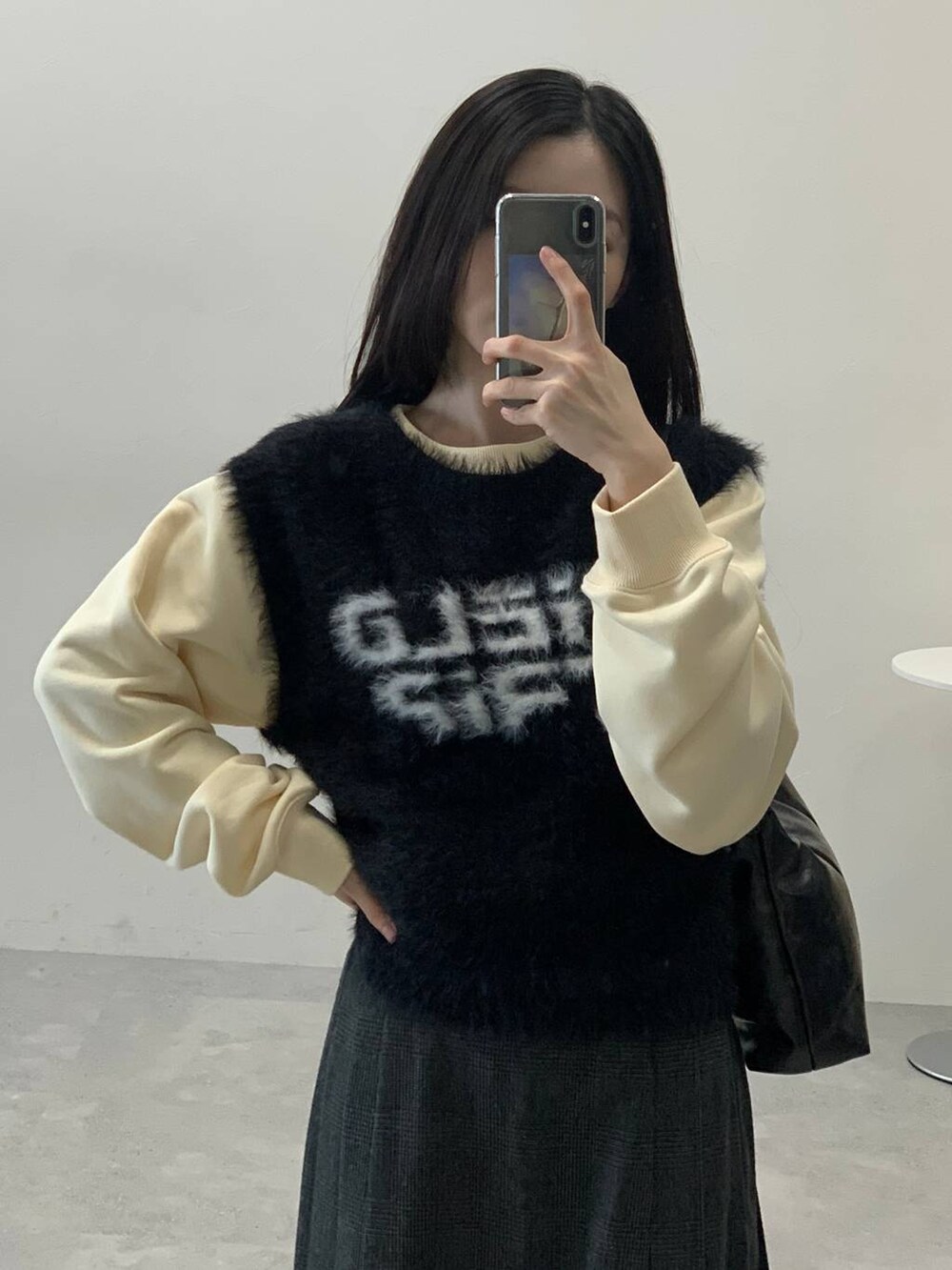 ベージュ系のスウェット、グレー系のスカート、ブラック系のハンドバッグを着用したレディースの冬コーディネートの6枚目の写真