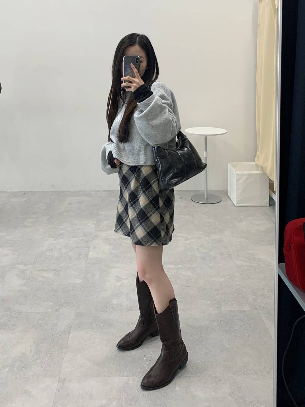 グレー系のニット/セーター、ブラック系のスカート、ブラック系のハンドバッグを着用したレディースの秋コーディネートの2枚目の写真