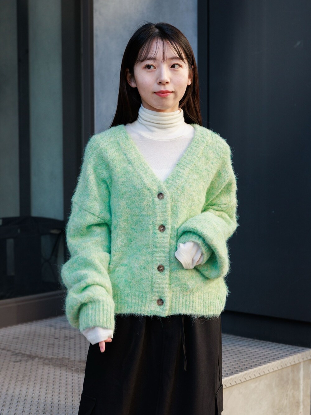 ブラック系のブーツ、ブラック系のスカート、グリーン系のカーディガン/ボレロを着用したレディースの冬コーディネートの5枚目の写真