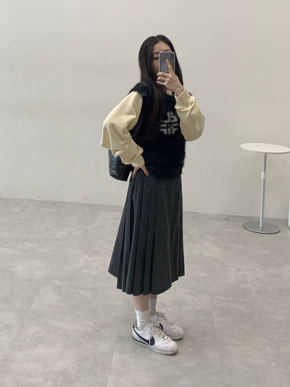ベージュ系のスウェット、グレー系のスカート、ブラック系のハンドバッグを着用したレディースの冬コーディネートの3枚目の写真