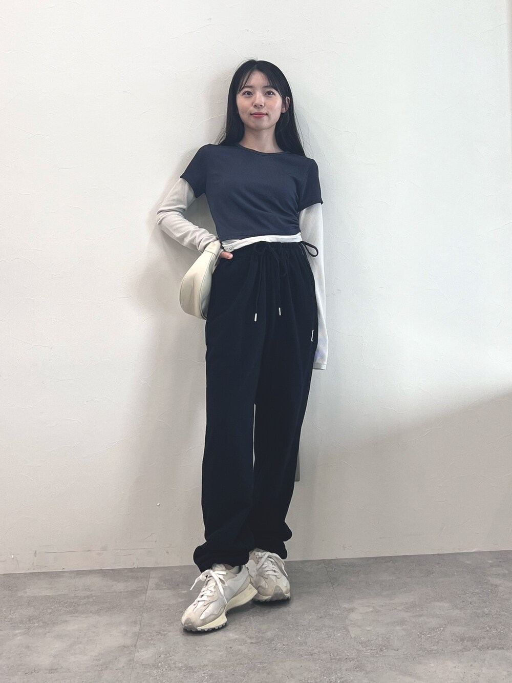 ホワイト系のスニーカー、ブラック系のスウェットパンツ、ホワイト系のショルダーバッグを着用したレディースの冬コーディネートの2枚目の写真
