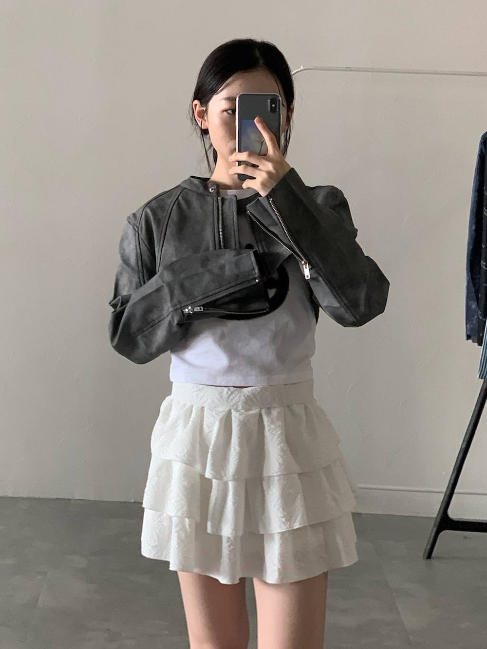グレー系のライダースジャケット、ホワイト系のスカート、ホワイト系のTシャツ/カットソーを着用したレディースの秋コーディネートの5枚目の写真