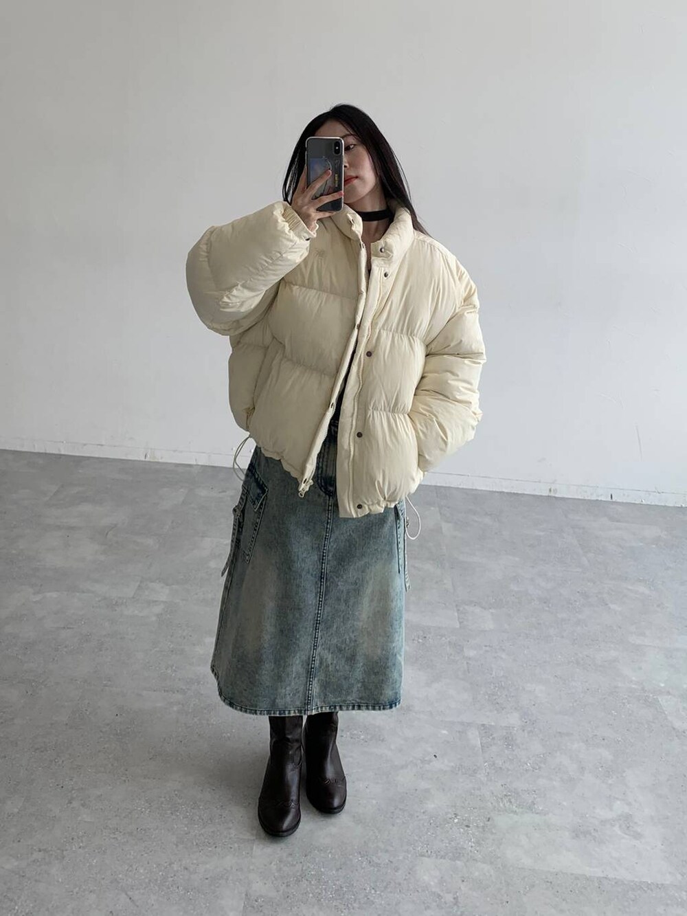 ブルー系のデニムスカート、ベージュ系のダウンジャケット/コートを着用したレディースの秋コーディネートの3枚目の写真