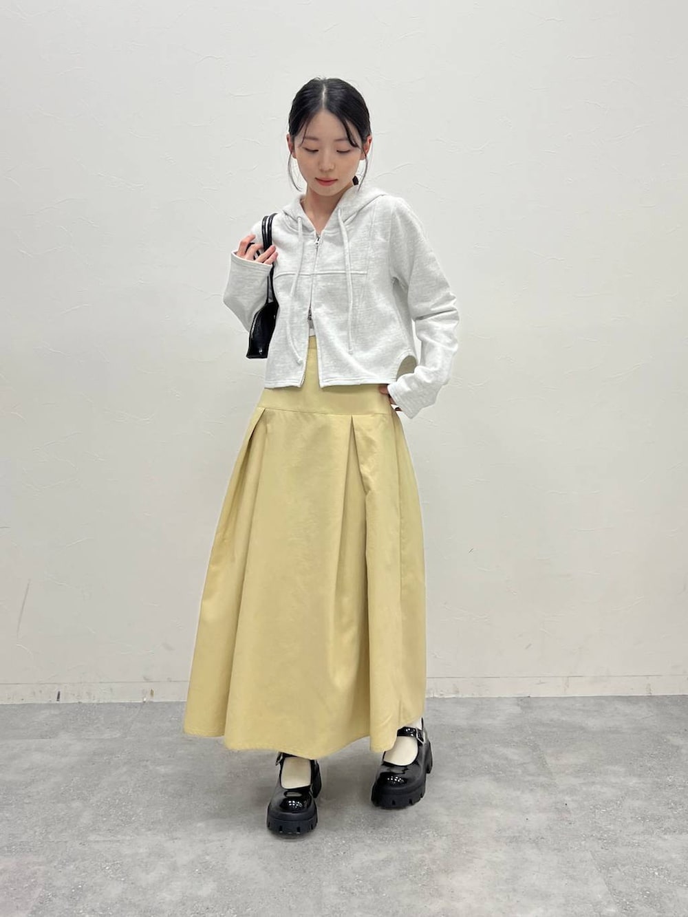 グレー系のスウェット、ベージュ系のスカート、ブラック系のハンドバッグを着用したレディースの冬コーディネートの4枚目の写真