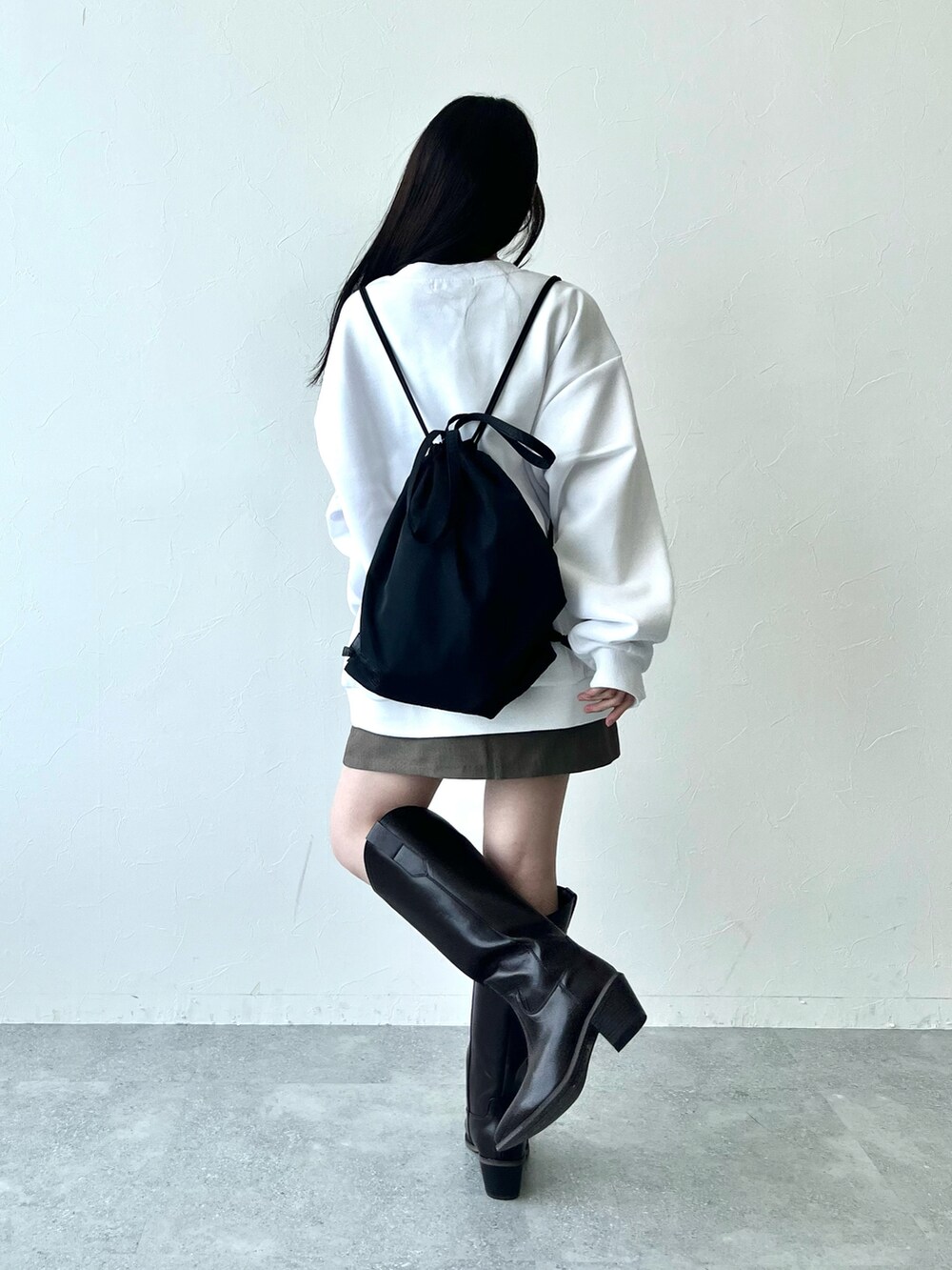 ブラック系のブーツ、ブラウン系のスカート、ホワイト系のスウェットを着用したレディースの冬コーディネートの4枚目の写真