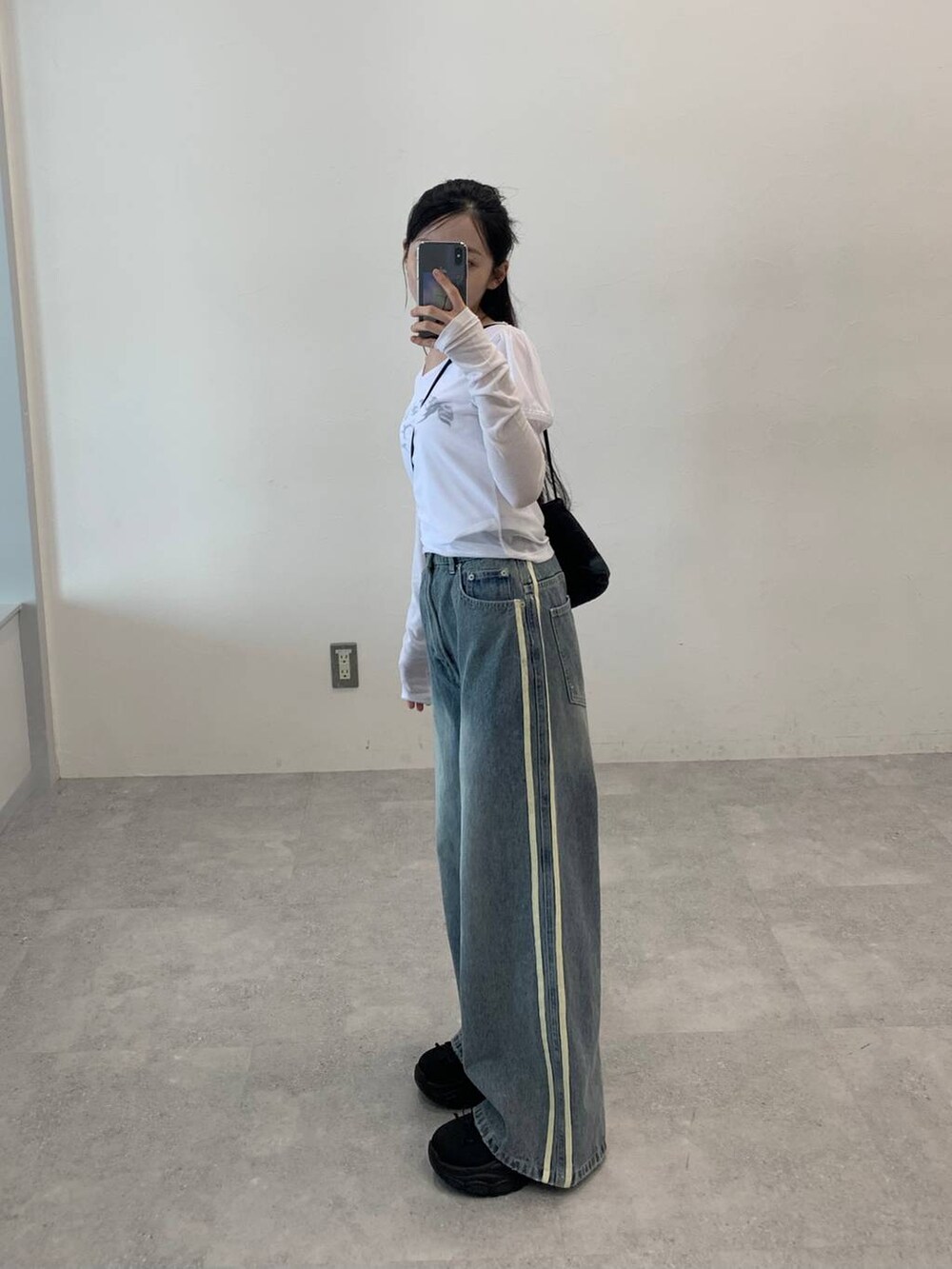 その他のデニムパンツ、ホワイト系のTシャツ/カットソー、ブラック系のショルダーバッグを着用したレディースの秋コーディネートの3枚目の写真