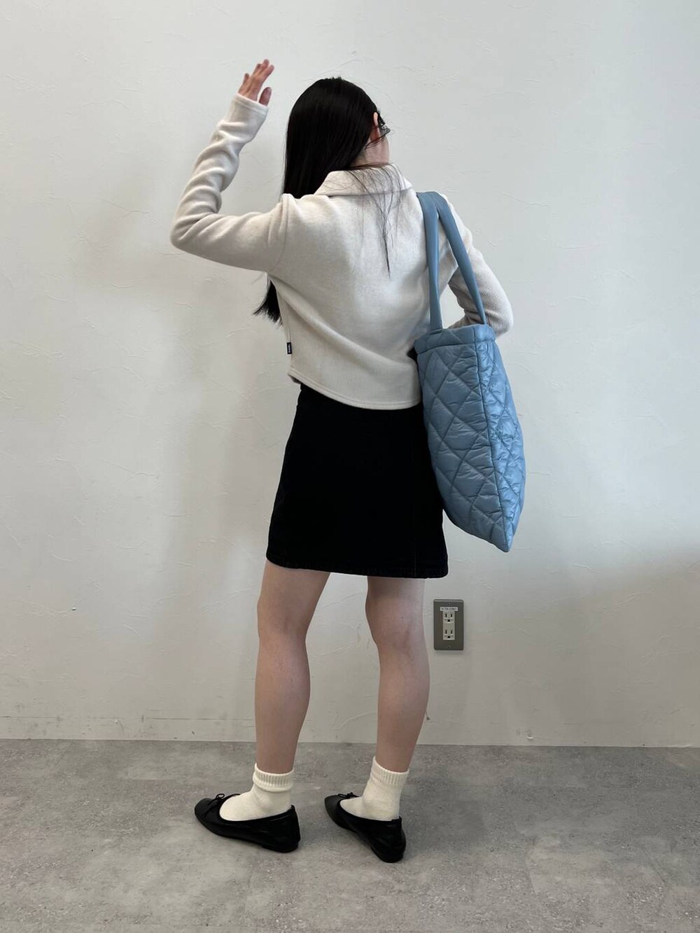 ブラック系のデニムスカート、ブラック系のバレエシューズ、ブルー系のトートバッグを着用したレディースの冬コーディネートの6枚目の写真