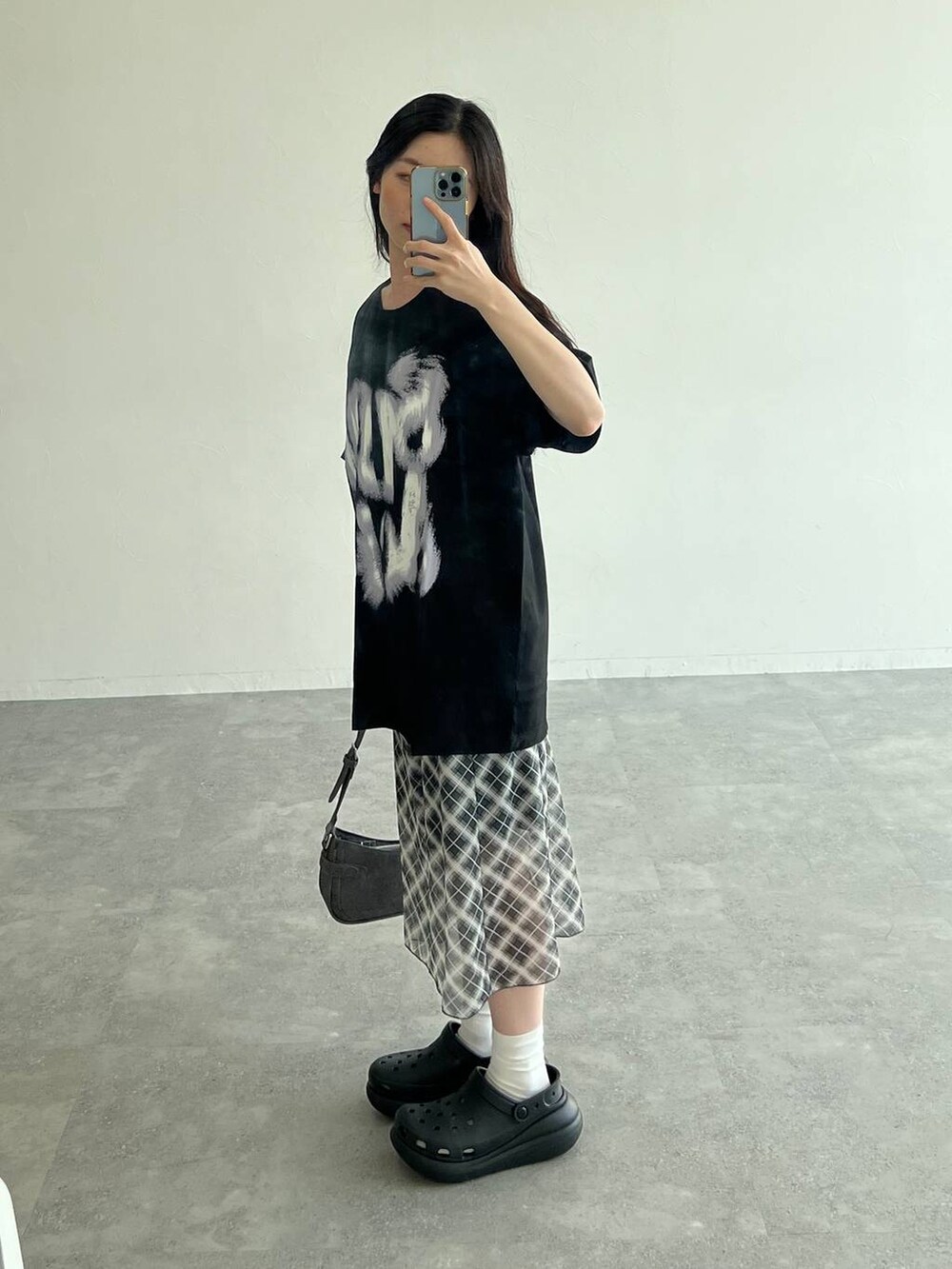 グレー系のスカート、ブラック系のトートバッグ、ブラック系のTシャツ/カットソーを着用したレディースの夏コーディネートの3枚目の写真