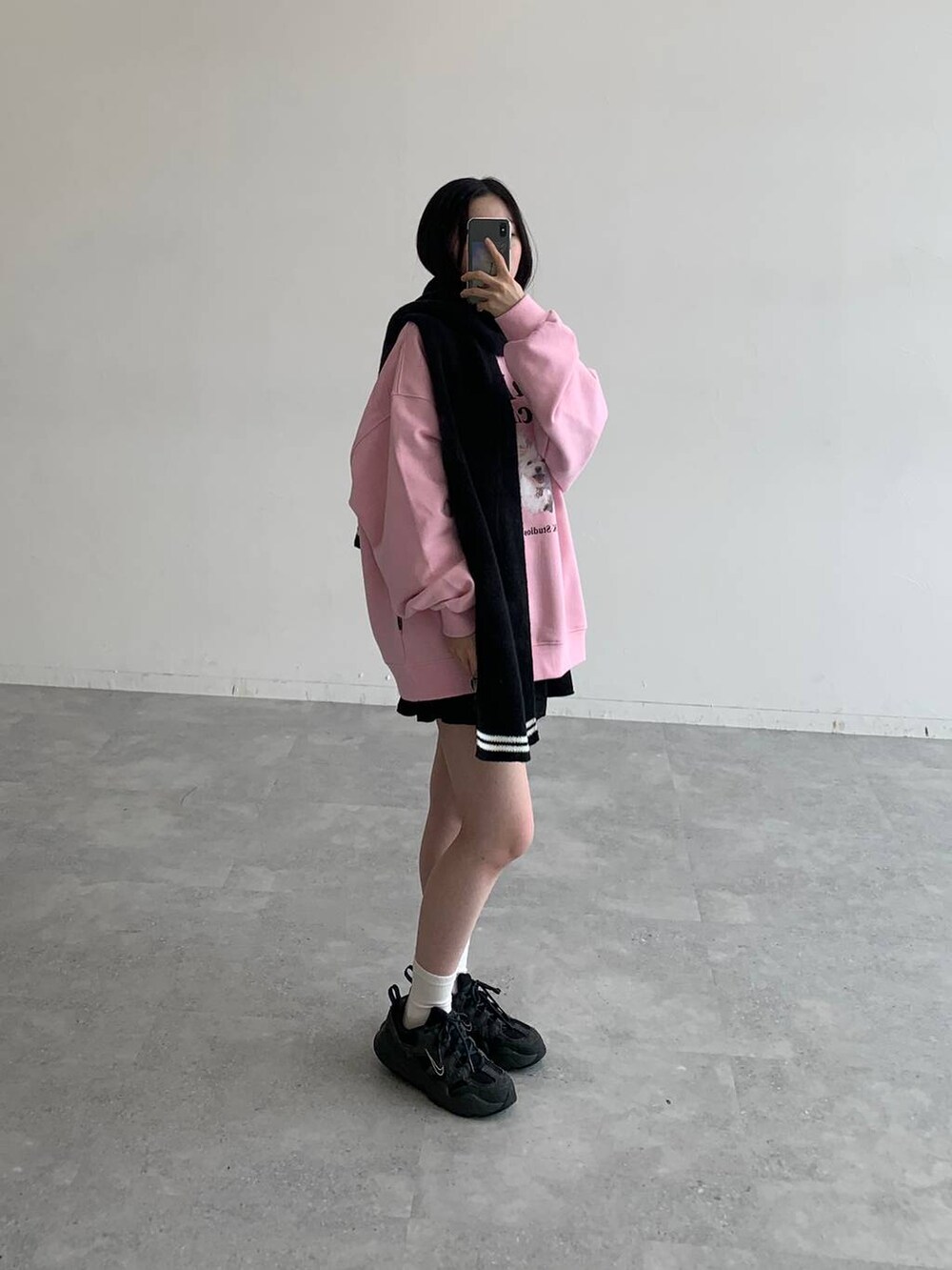 ブラック系のスカート、ピンク系のスウェット、ブラック系のマフラーを着用したレディースの秋コーディネートの2枚目の写真