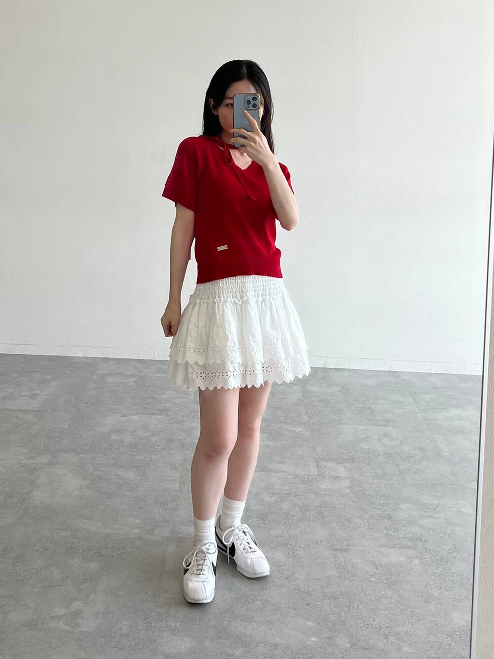 ホワイト系のスカート、ブラック系のトートバッグ、レッド系のニット/セーターを着用したレディースの夏コーディネートの2枚目の写真