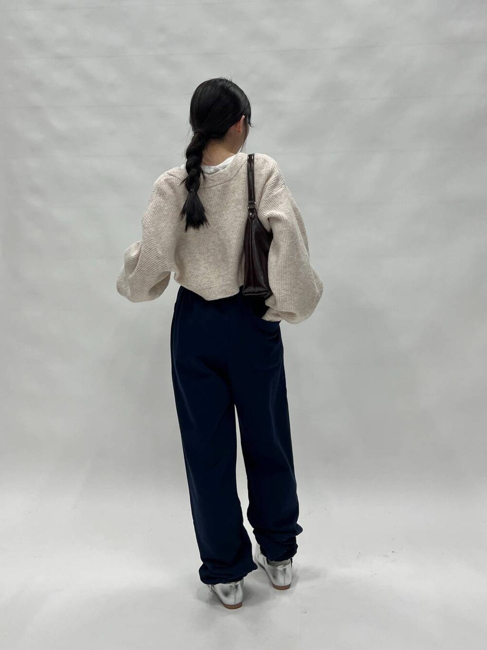 ブラック系のスウェットパンツ、ピンク系のカーディガン/ボレロ、ブラウン系のバッグを着用したレディースの冬コーディネートの5枚目の写真