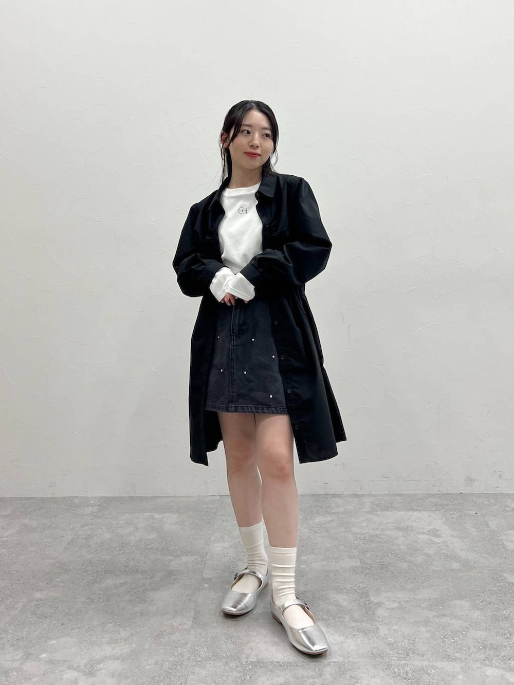 ホワイト系のTシャツ/カットソー、ブラック系のデニムスカート、ブラック系のワンピースを着用したレディースの春コーディネートの2枚目の写真