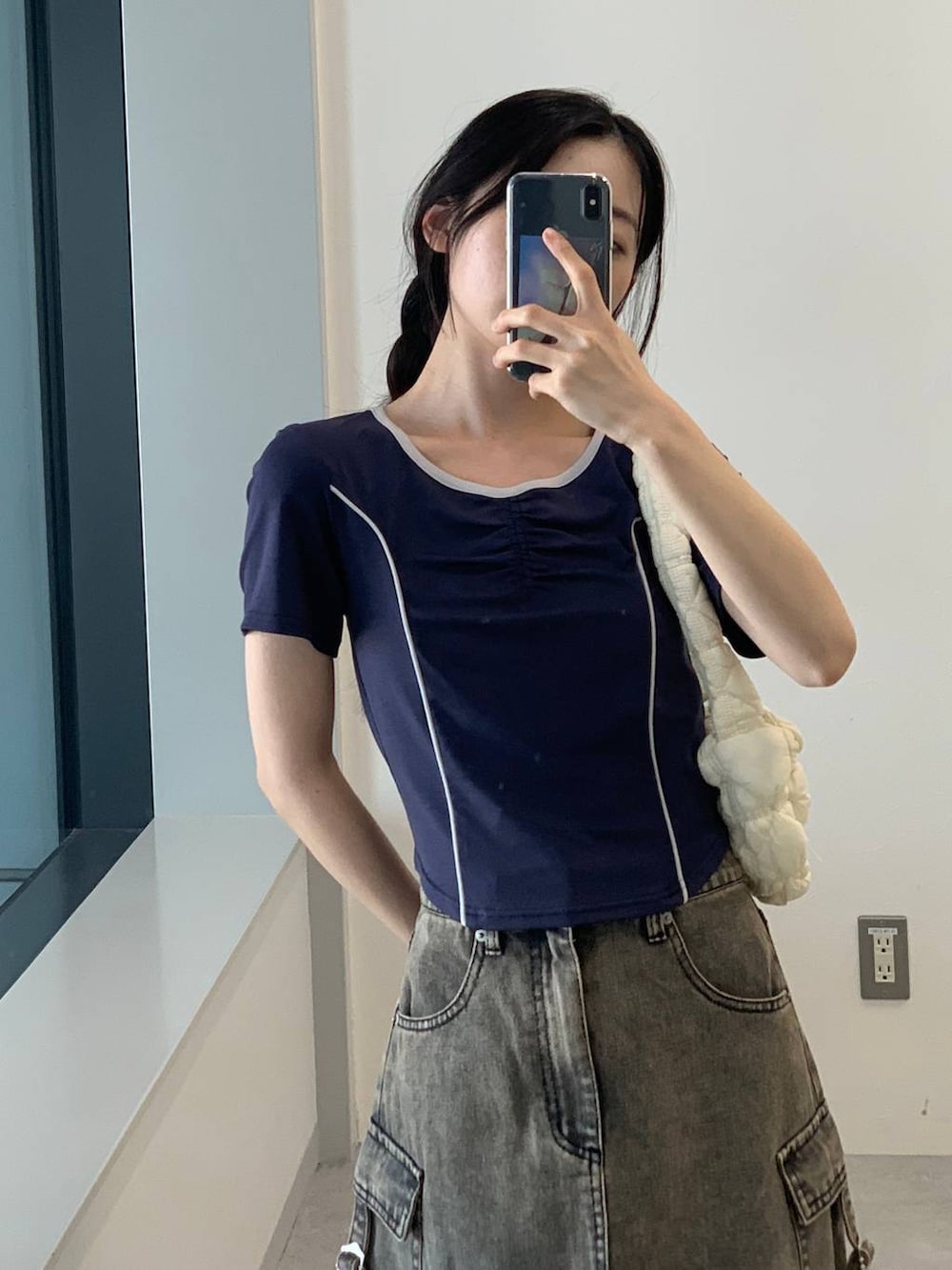 ブラック系のデニムスカート、ホワイト系のショルダーバッグ、ブルー系のTシャツ/カットソーを着用したレディースの夏コーディネートの6枚目の写真