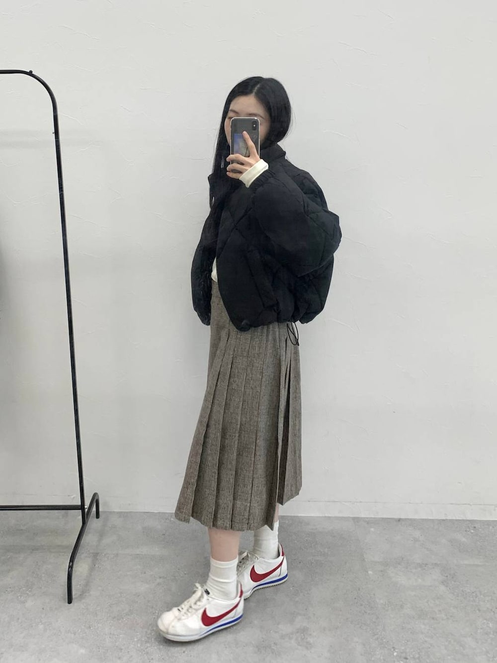 ブラウン系のスカート、ベージュ系のTシャツ/カットソー、ブラック系のダウンジャケット/コートを着用したレディースの冬コーディネートの2枚目の写真