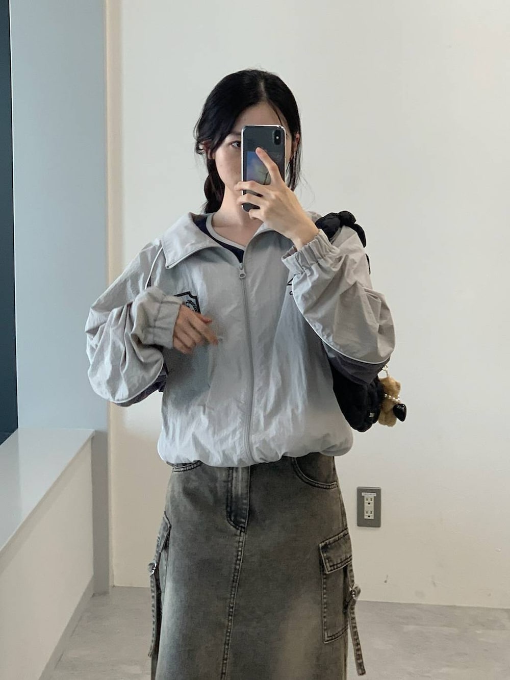 グレー系のナイロンジャケット、ブラック系のデニムスカート、ブラック系のショルダーバッグを着用したレディースの夏コーディネートの5枚目の写真