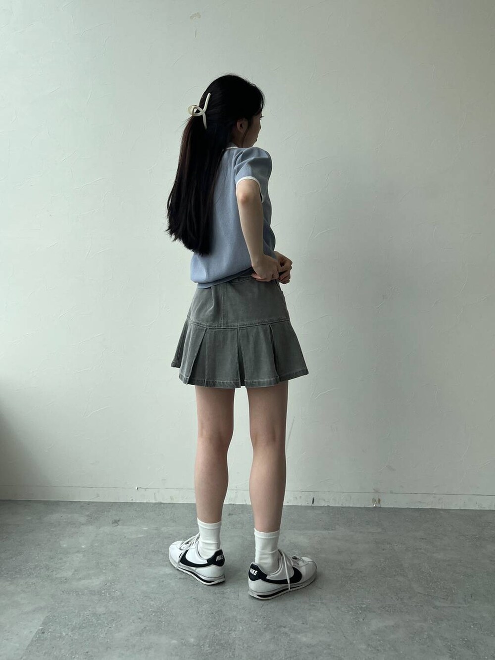 ブルー系のニット/セーター、グレー系のデニムスカートを着用したレディースの夏コーディネートの5枚目の写真