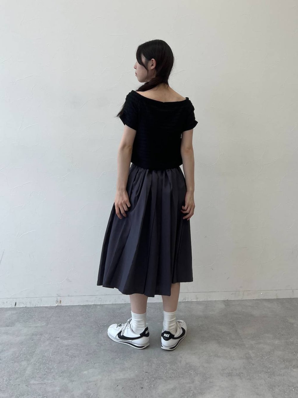 グレー系のスカート、ブラック系のTシャツ/カットソーを着用したレディースの夏コーディネートの2枚目の写真