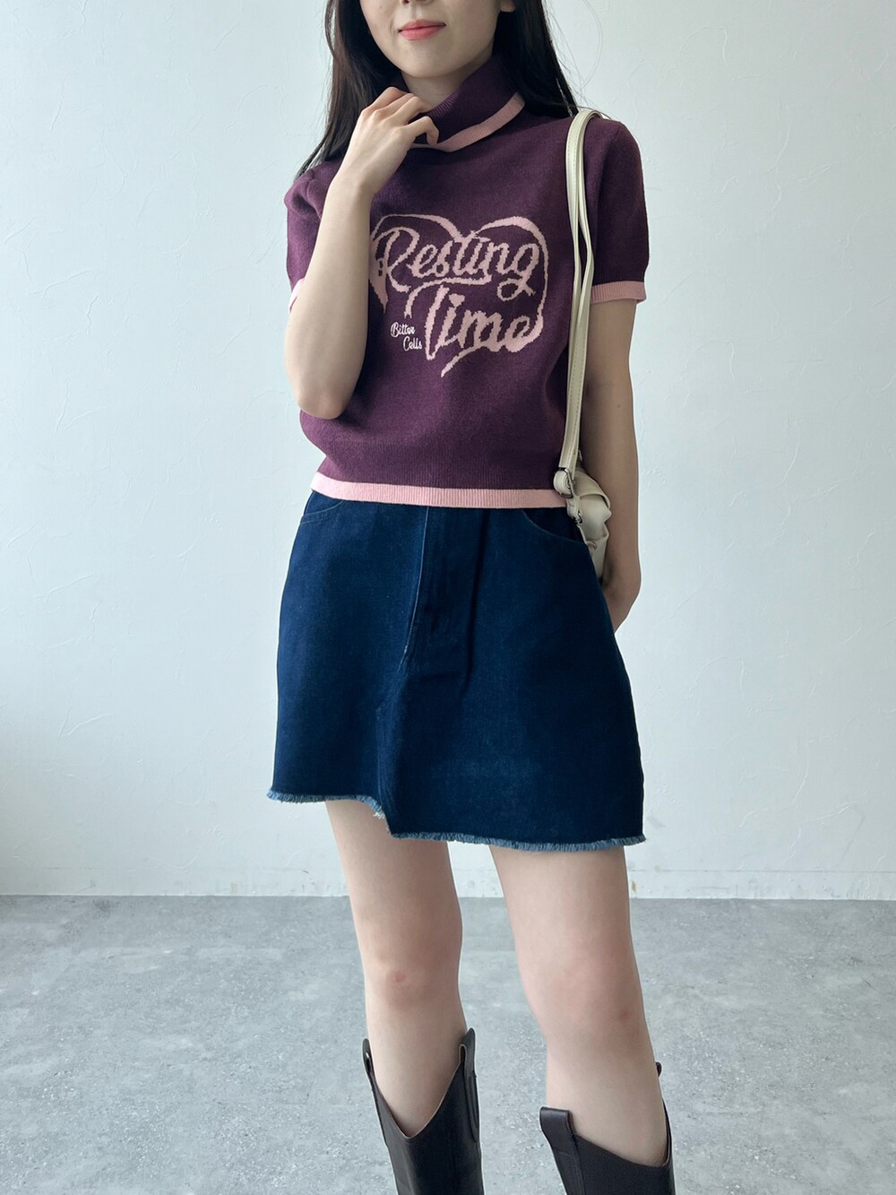 ベージュ系のショルダーバッグ、パープル系のニット/セーター、ブルー系のデニムスカートを着用したレディースの冬コーディネートの2枚目の写真