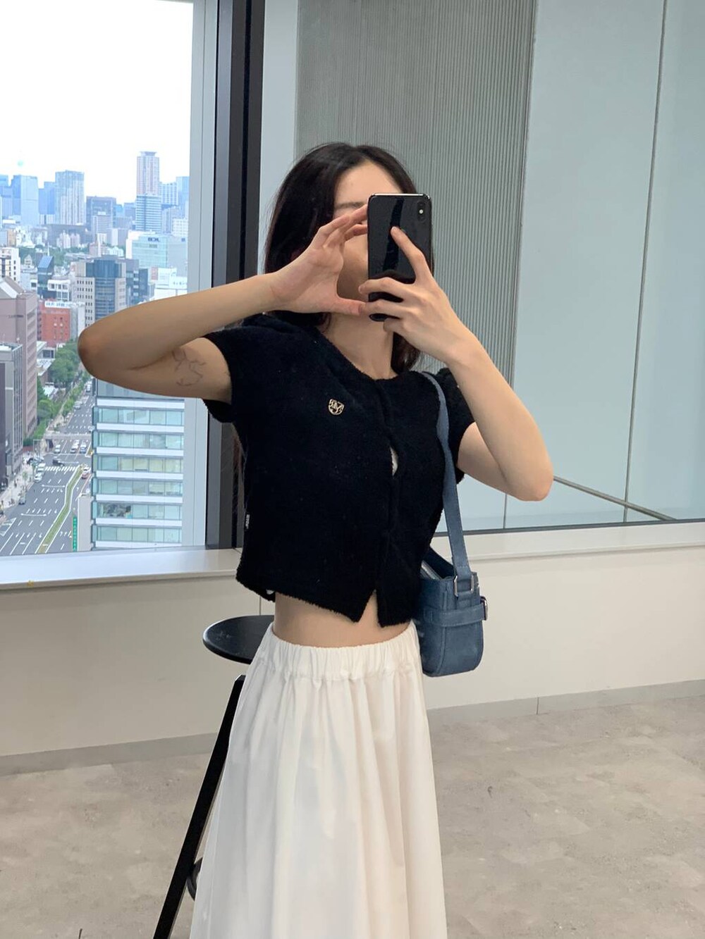 ホワイト系のスカート、ブルー系のトートバッグ、ブラック系のカーディガン/ボレロを着用したレディースの夏コーディネートの2枚目の写真