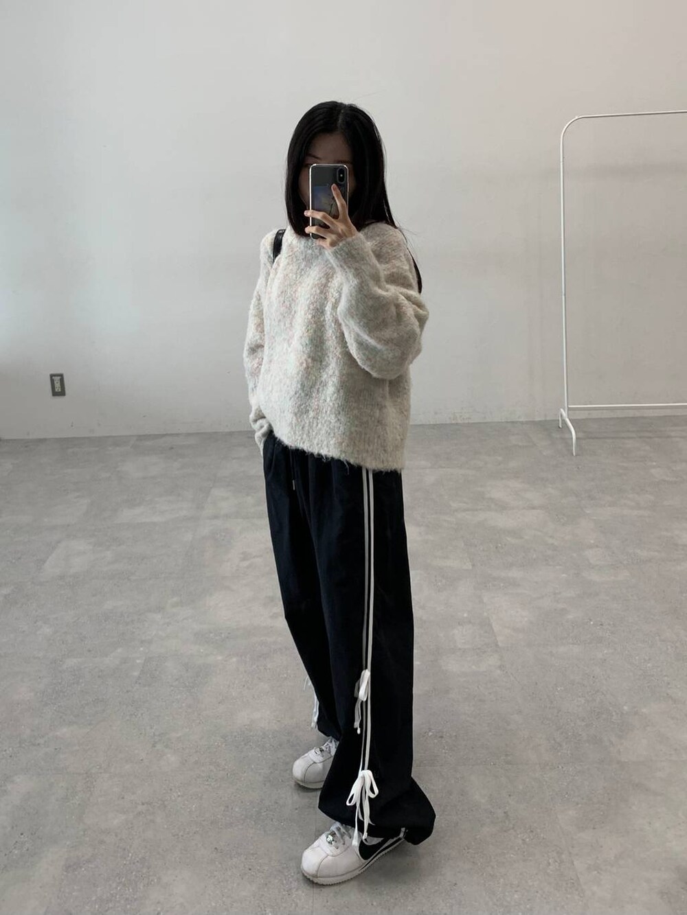 ブラック系のその他パンツ、ホワイト系のニット/セーター、ブラック系のハンドバッグを着用したレディースの秋コーディネートの5枚目の写真