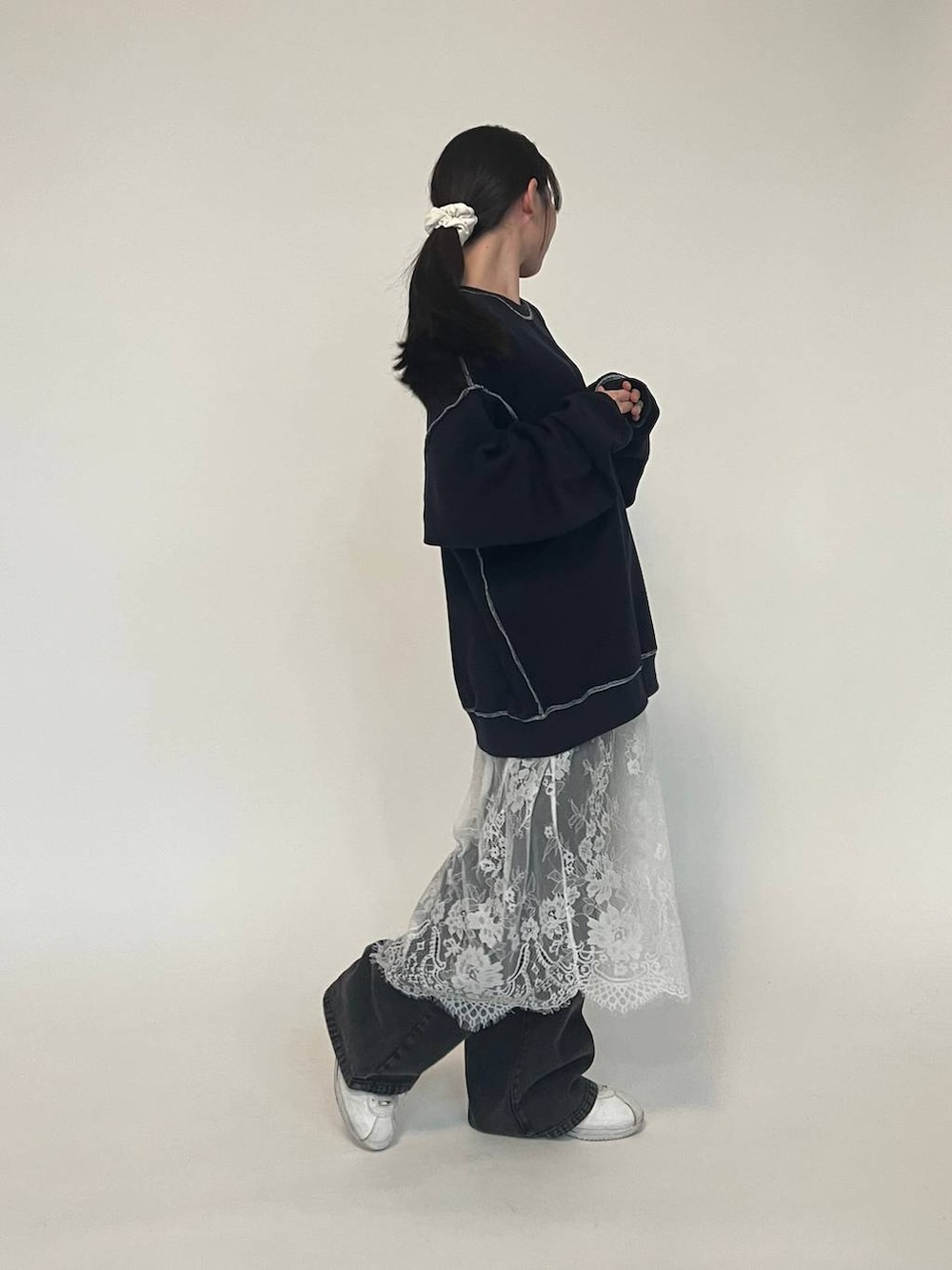 ブラック系のデニムパンツ、ブルー系のパーカー、ホワイト系のスニーカーを着用したレディースの冬コーディネートの5枚目の写真