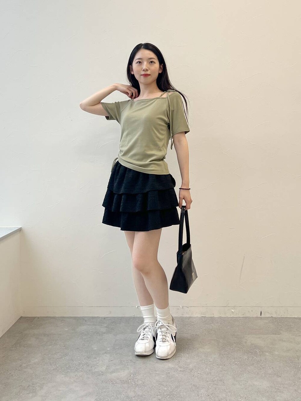 グリーン系のTシャツ/カットソー、ブラック系のハンドバッグ、ブラック系のスカートを着用したレディースの夏コーディネートの6枚目の写真