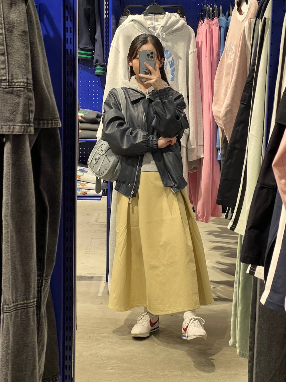 ベージュ系のスカート、ブルー系のブルゾン、グレー系のパーカーを着用したレディースの春コーディネートの3枚目の写真