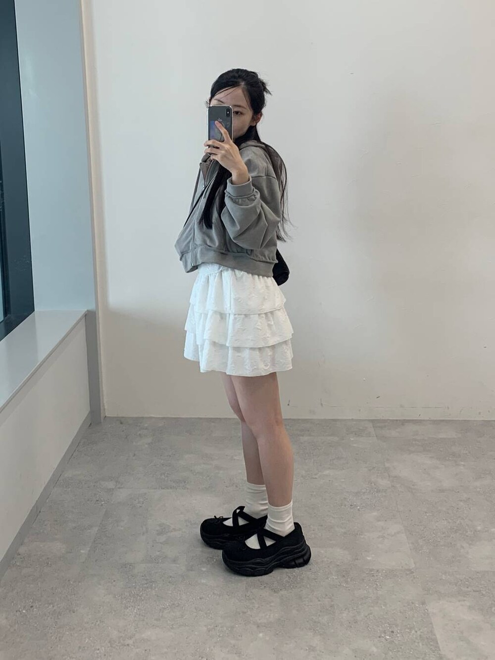 グレー系のパーカー、ホワイト系のスカートを着用したレディースの秋コーディネートの5枚目の写真