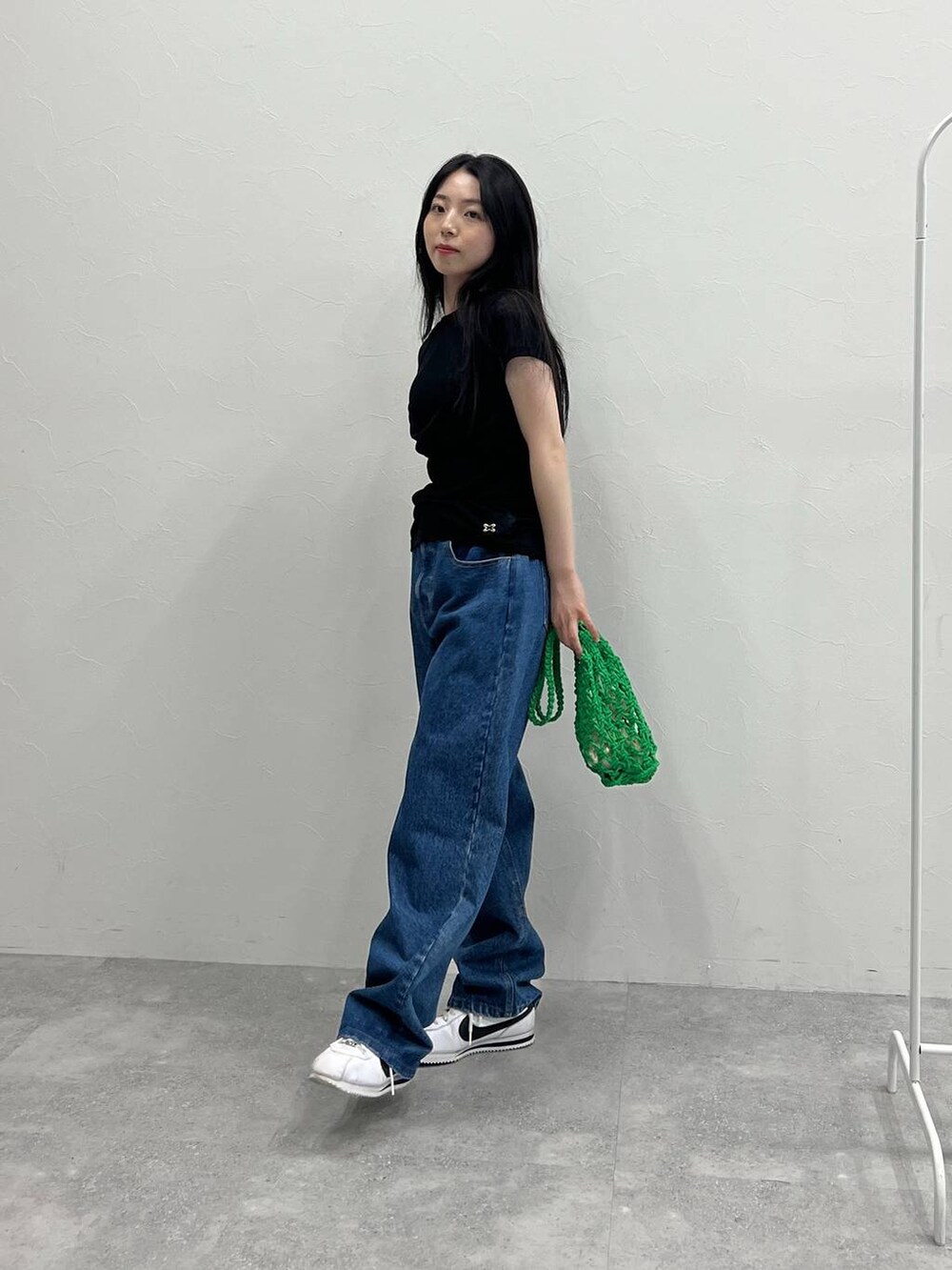 グリーン系のトートバッグ、ブルー系のデニムパンツ、ブラック系のTシャツ/カットソーを着用したレディースの夏コーディネートの3枚目の写真
