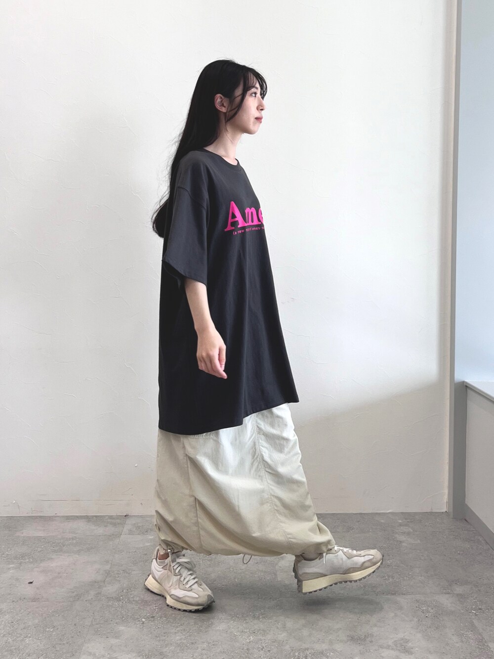 グレー系のTシャツ/カットソー、ブラック系のスカート、ホワイト系のスニーカーを着用したレディースの夏コーディネートの2枚目の写真