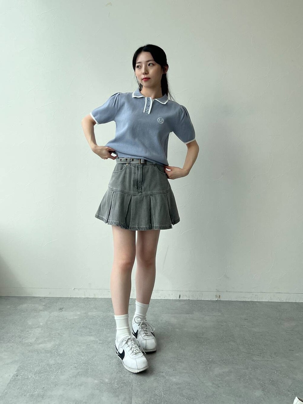 ブルー系のニット/セーター、グレー系のデニムスカートを着用したレディースの夏コーディネートの2枚目の写真