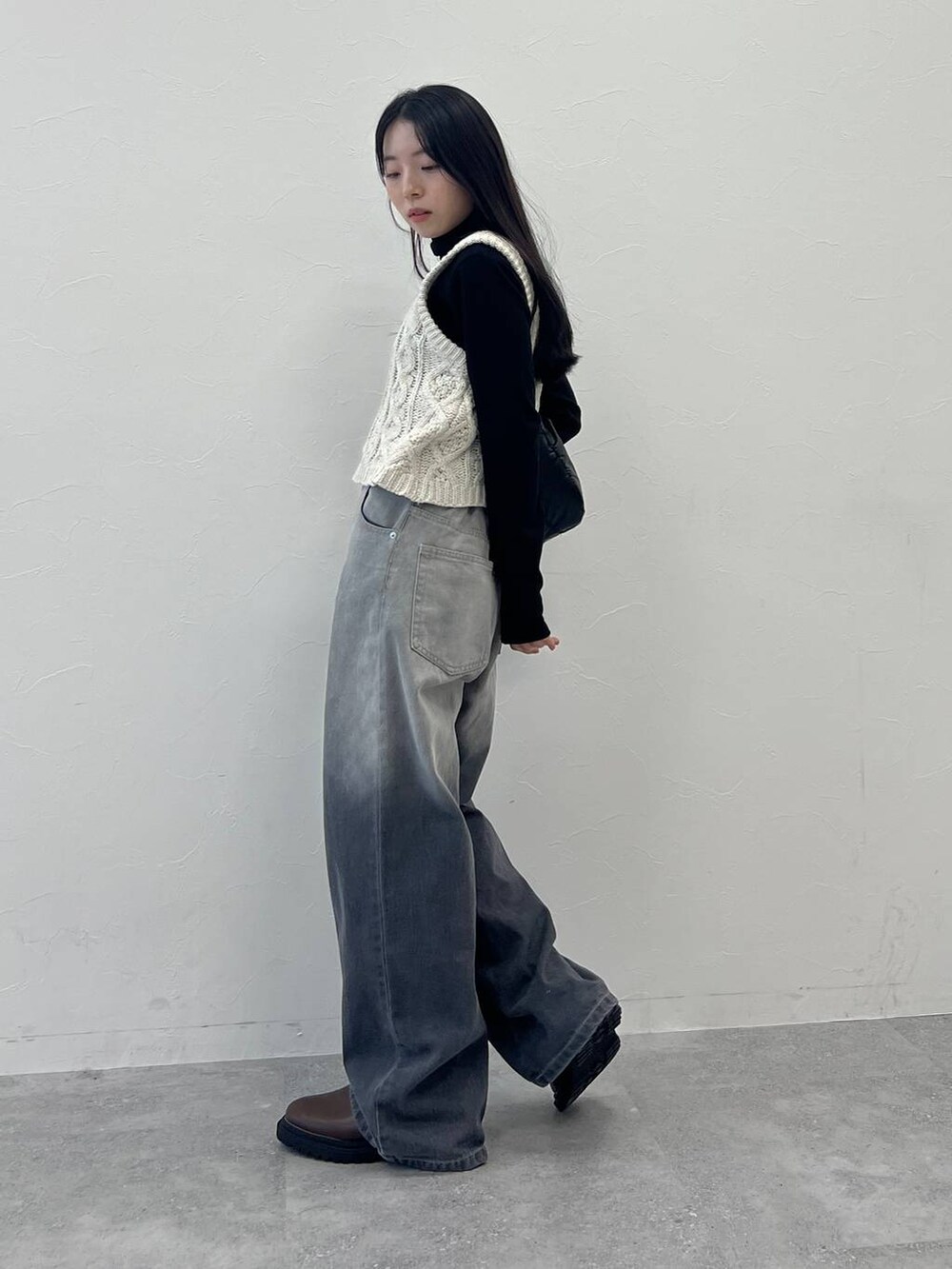 ブラック系のショルダーバッグ、ブラック系のデニムパンツ、ベージュ系のベストを着用したレディースの冬コーディネートの4枚目の写真