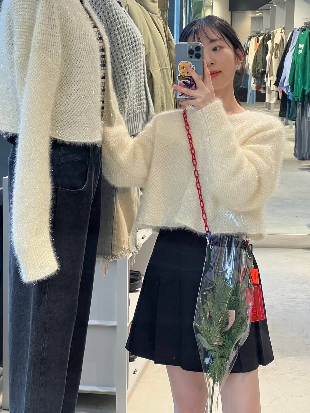 ブラック系のブーツ、ホワイト系のカーディガン/ボレロ、ブラック系のスカートを着用したレディースの冬コーディネートの3枚目の写真