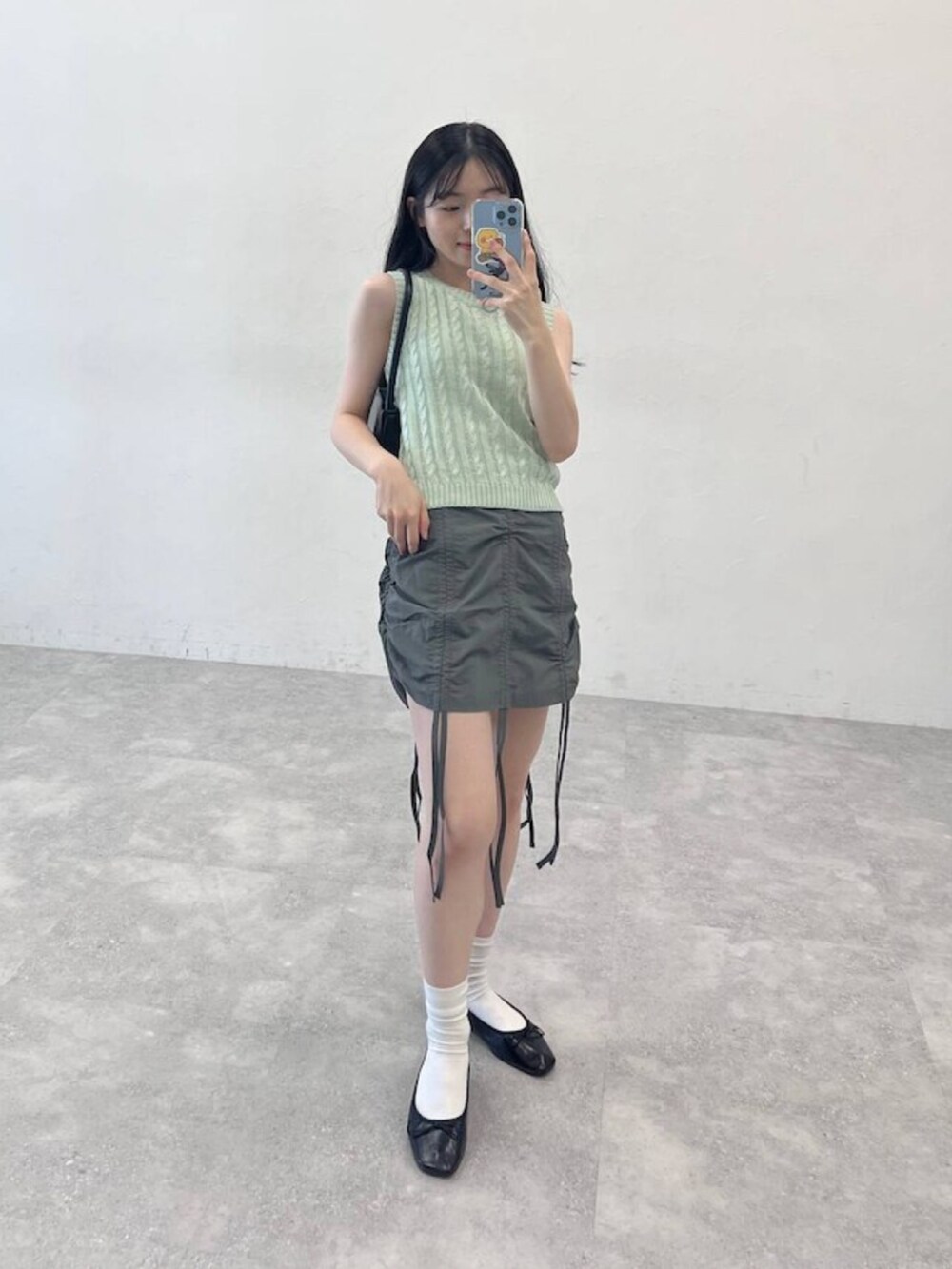 ブラック系のバレエシューズ、グリーン系のスカート、グリーン系のニット/セーターを着用したレディースの夏コーディネートの3枚目の写真