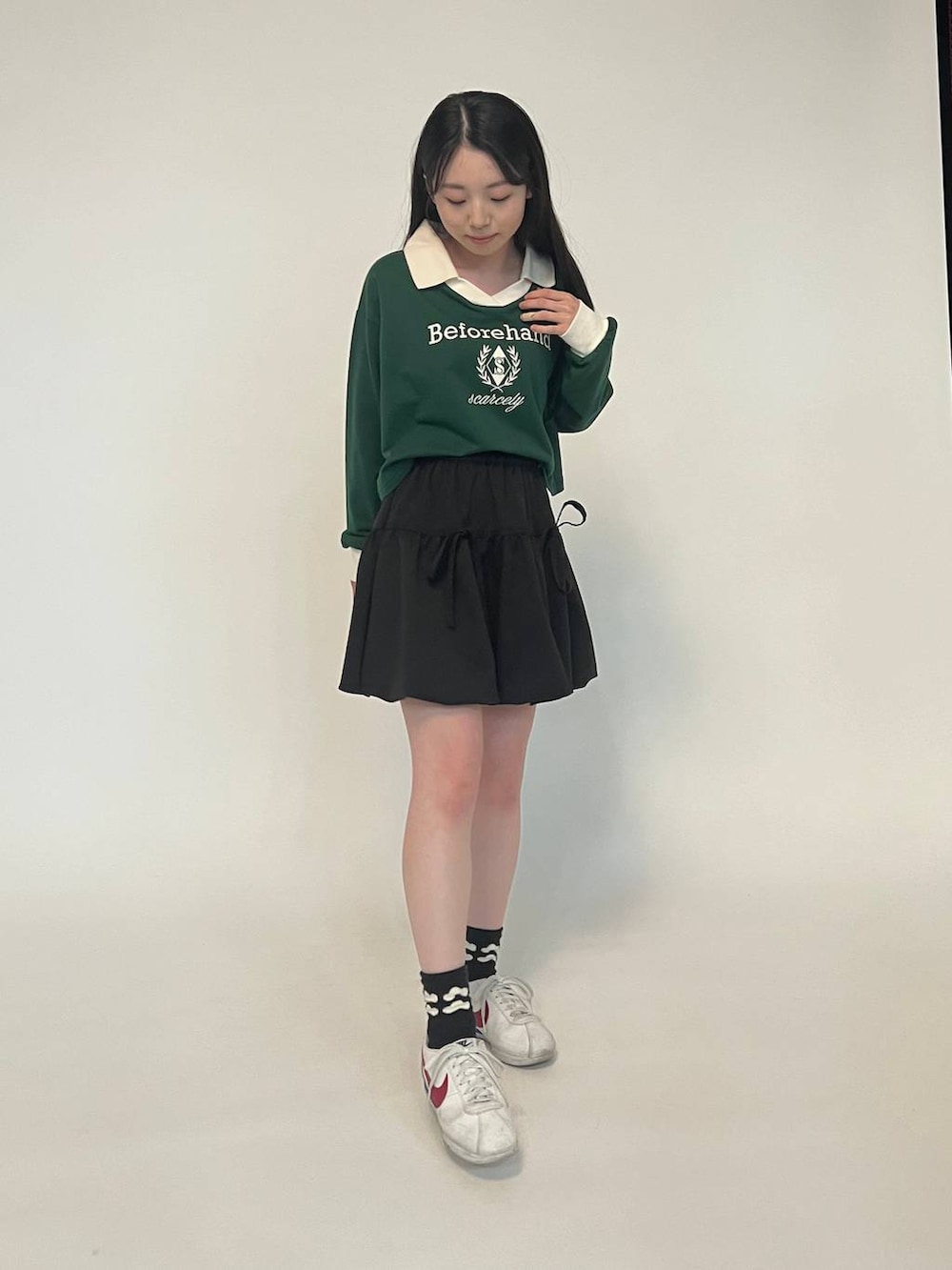 ブラック系のスカート、グリーン系のスウェットを着用したレディースの春コーディネートの2枚目の写真
