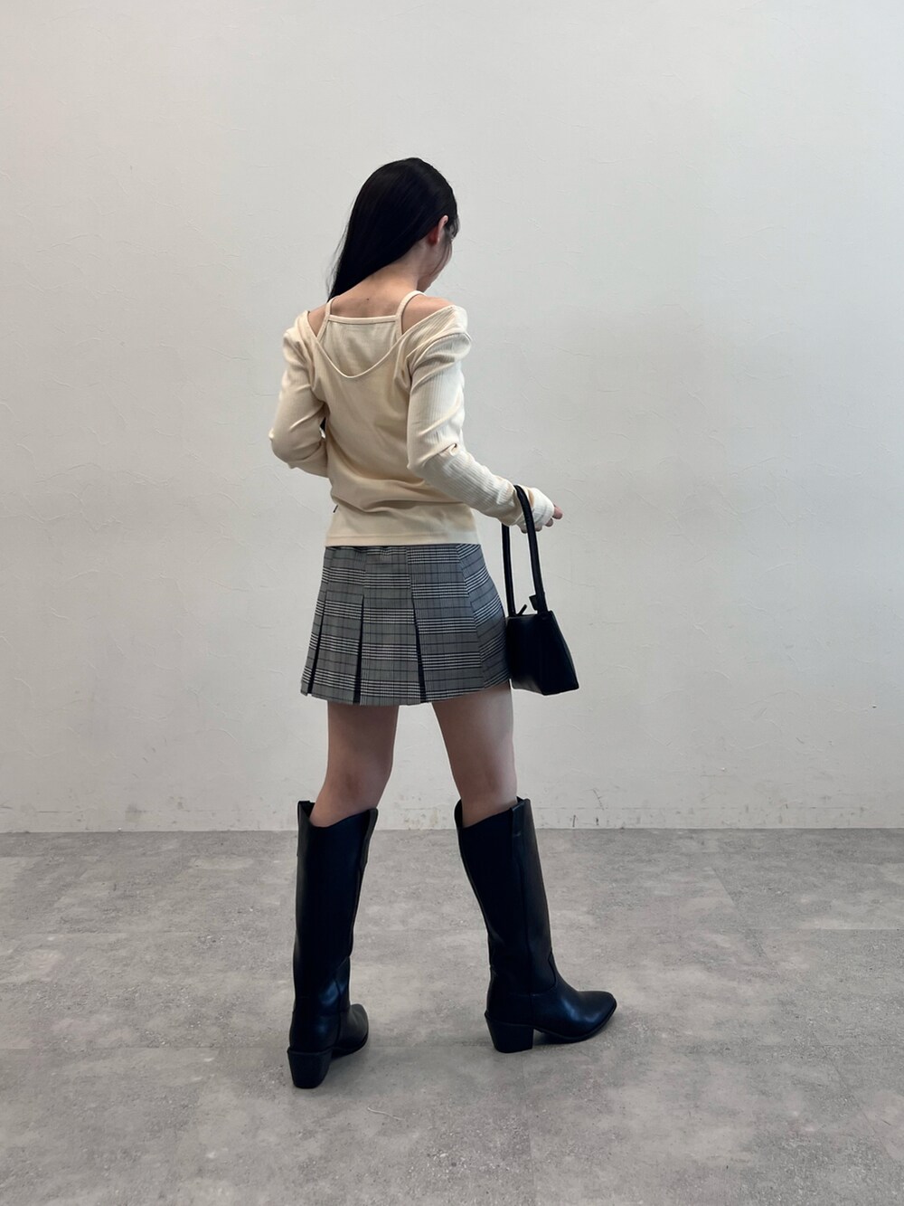 ブラック系のブーツ、ブラック系のショルダーバッグ、グレー系のスカートを着用したレディースの冬コーディネートの2枚目の写真