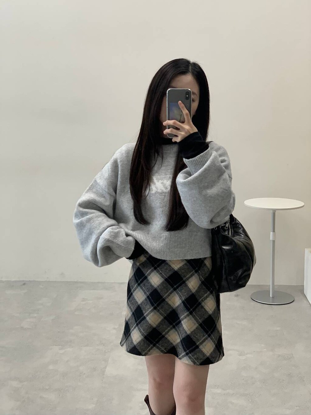 グレー系のニット/セーター、ブラック系のスカート、ブラック系のハンドバッグを着用したレディースの秋コーディネートの4枚目の写真