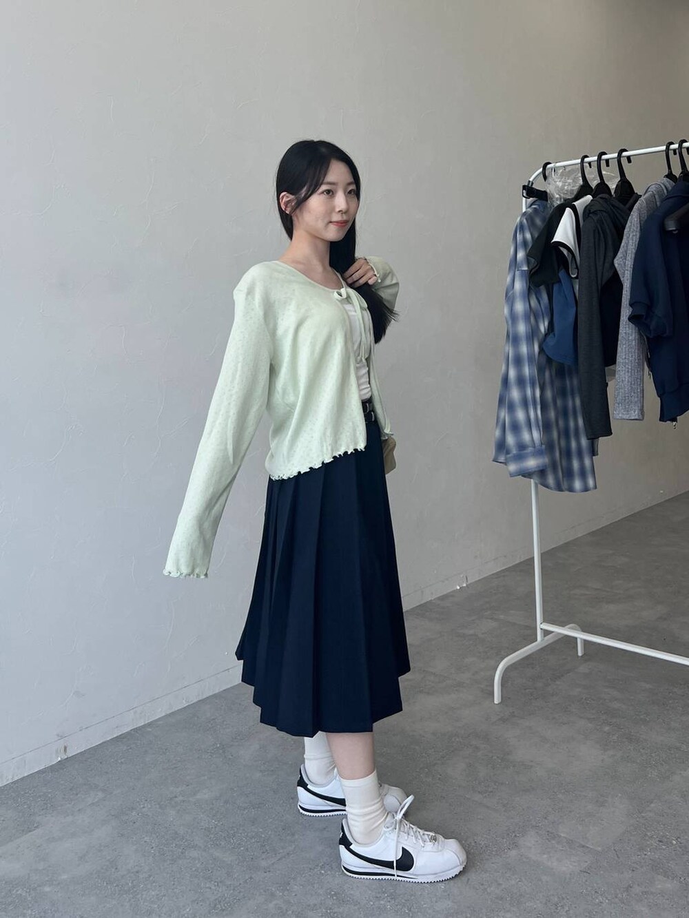 ベージュ系のバックパック/リュック、ブルー系のスカート、グリーン系のカーディガン/ボレロを着用したレディースの春コーディネートの6枚目の写真