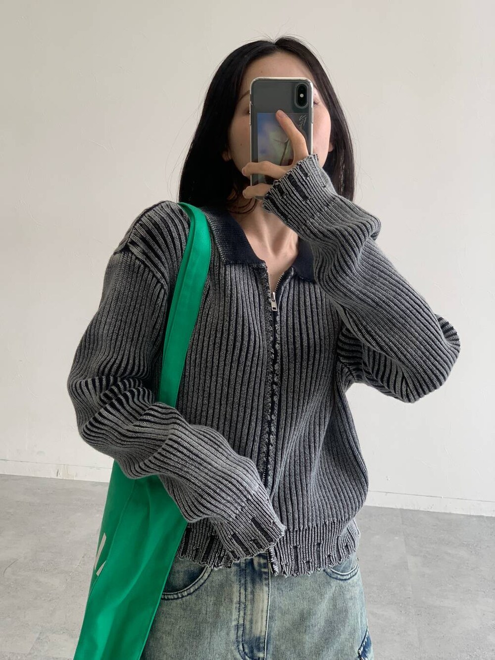 ブルー系のデニムスカート、グリーン系のトートバッグ、ブラック系のニット/セーターを着用したレディースの秋コーディネートの3枚目の写真